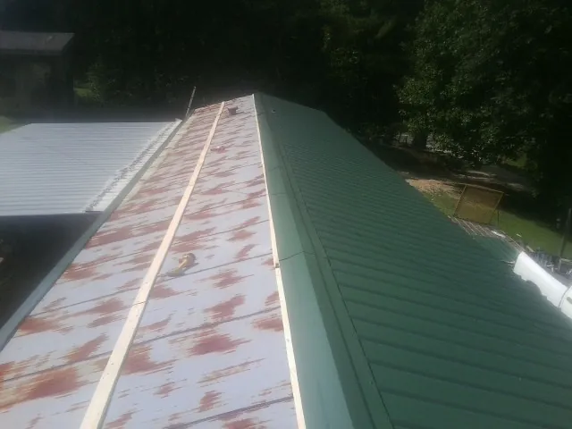Old rusted panels beside newly installed green metal roofing — Wind Damage Roof Repair by Roofing Brothers in Seibert