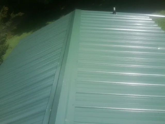 New green metal panels meeting at the ridge of a roof — Flat Roof Repair work by our crew in Seibert