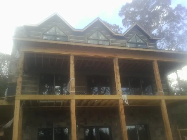 Dormers and porch framing on a large log home under construction — Roof Coating work by our crew in Seibert