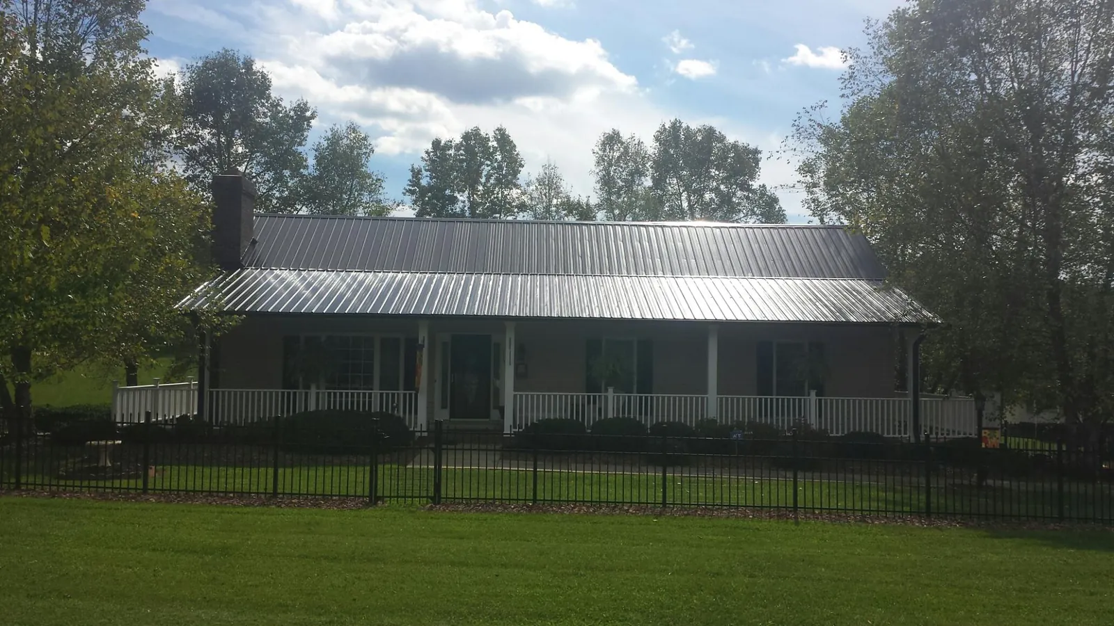 Gray metal roof on a brick ranch with a full width front porch — Gutter Guard Installation work by our crew in Seibert