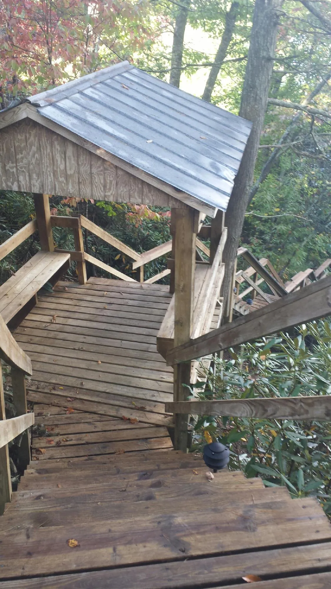 Metal roofed shelter over wooden steps on a wooded walkway — Skylight Repair & Installation work by our crew in Seibert