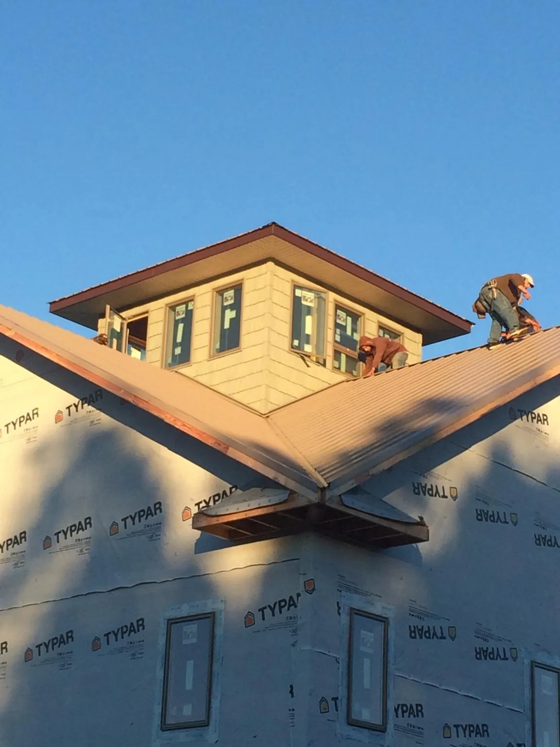 Roofers working around a rooftop cupola on a new metal roof at sunset — Roof Waterproofing in Seibert by Roofing Brothers